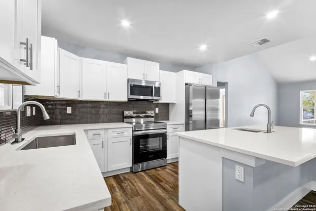 a kitchen with stainless steel appliances granite countertop a sink a stove top oven a refrigerator with granite countertops and cabinets