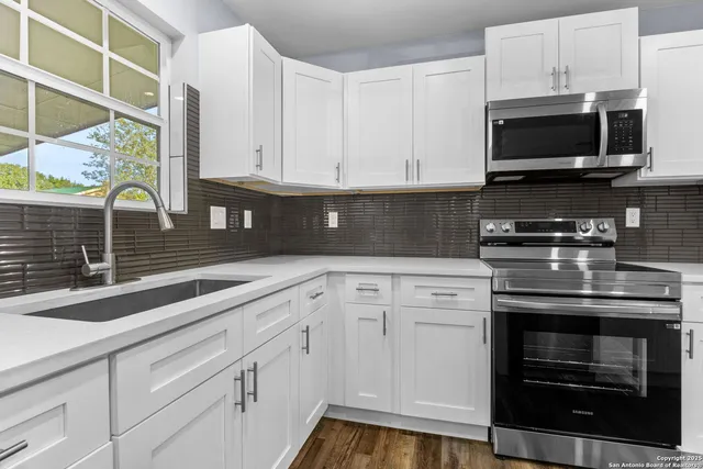 a kitchen with stainless steel appliances white cabinets and a stove a oven with wooden floor