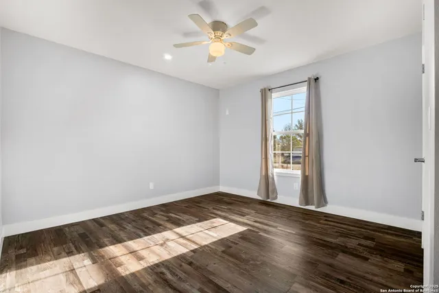 a view of empty room with wooden floor and fan