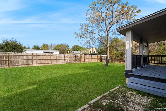 a view of a deck with a big yard potted plants and large tree