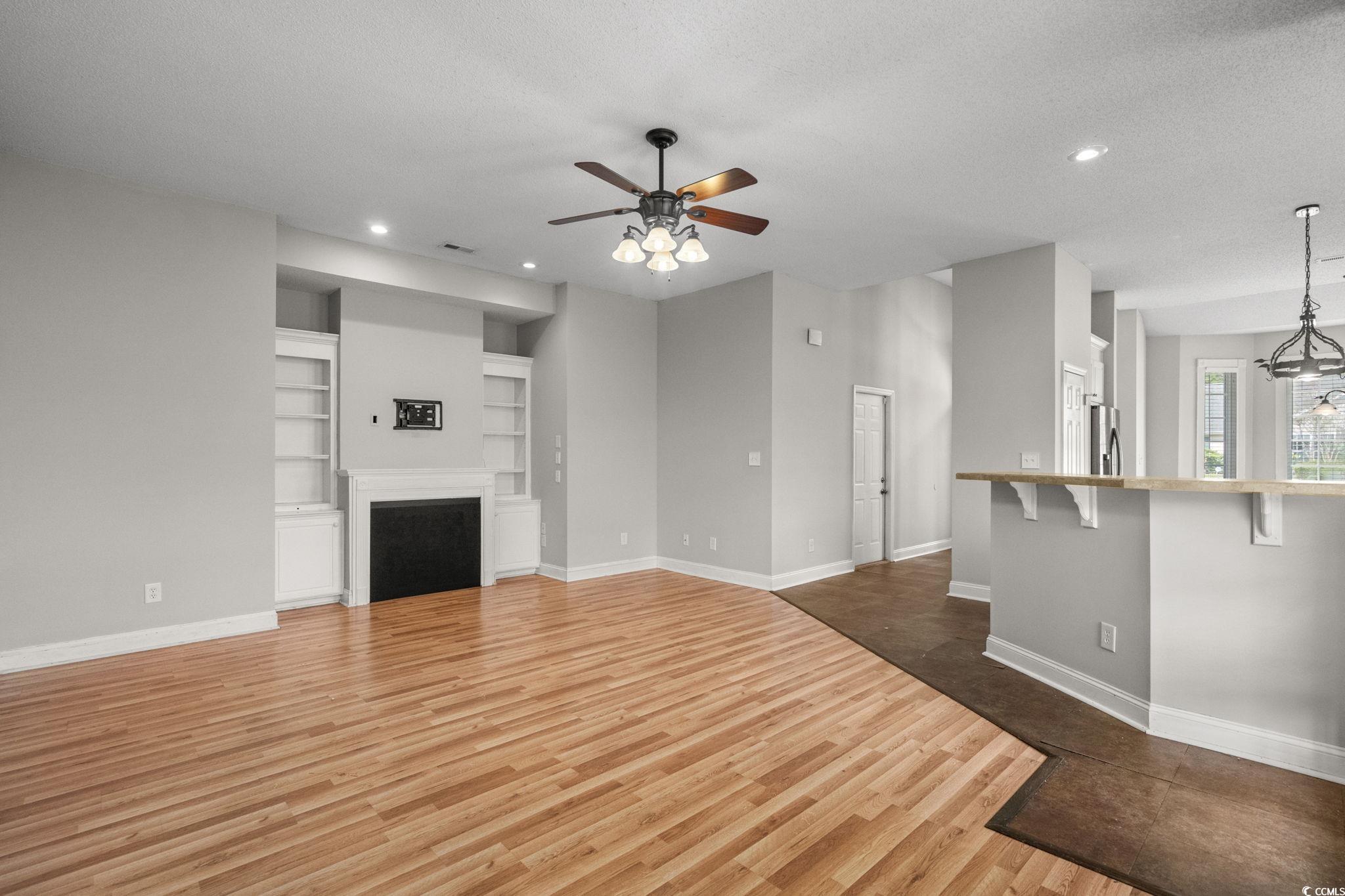 2723 Canvasback Trail Myrtle Beach, SC 29588 - Photo 10 of 40 Unfurnished living room with dark wood-type flooring, built in shelves, a ceiling fan, recessed lighting, and a textured ceiling