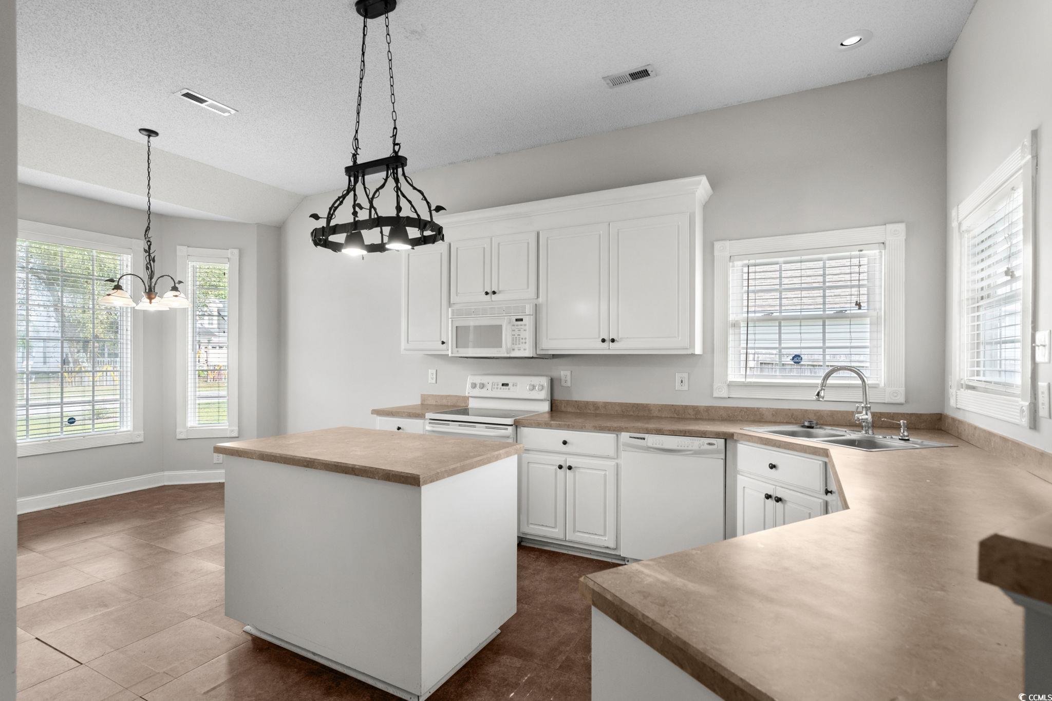 2723 Canvasback Trail Myrtle Beach, SC 29588 - Photo 12 of 40 Kitchen with a center island, white cabinetry, white appliances, pendant lighting, and light countertops