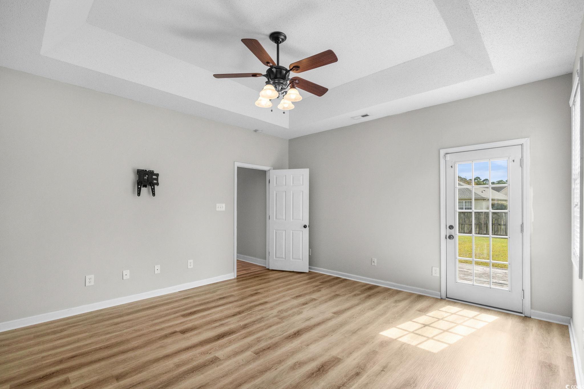 2723 Canvasback Trail Myrtle Beach, SC 29588 - Photo 19 of 40 Empty room featuring a raised ceiling, light wood-style flooring, and ceiling fan