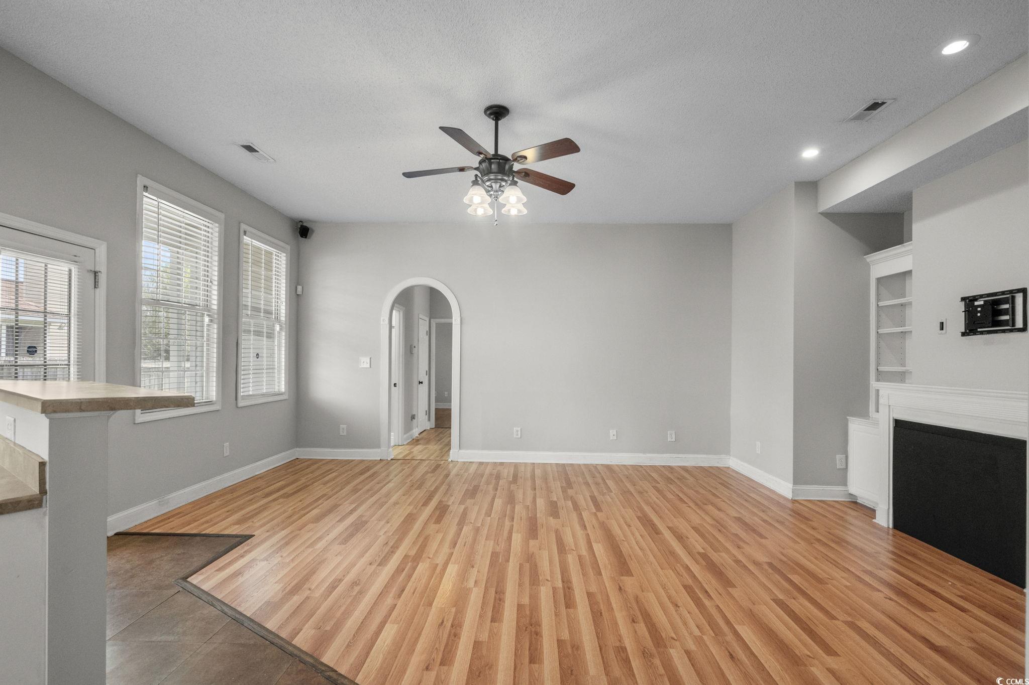 2723 Canvasback Trail Myrtle Beach, SC 29588 - Photo 5 of 40 Unfurnished living room featuring a textured ceiling, light wood-style floors, arched walkways, a ceiling fan, and built in features
