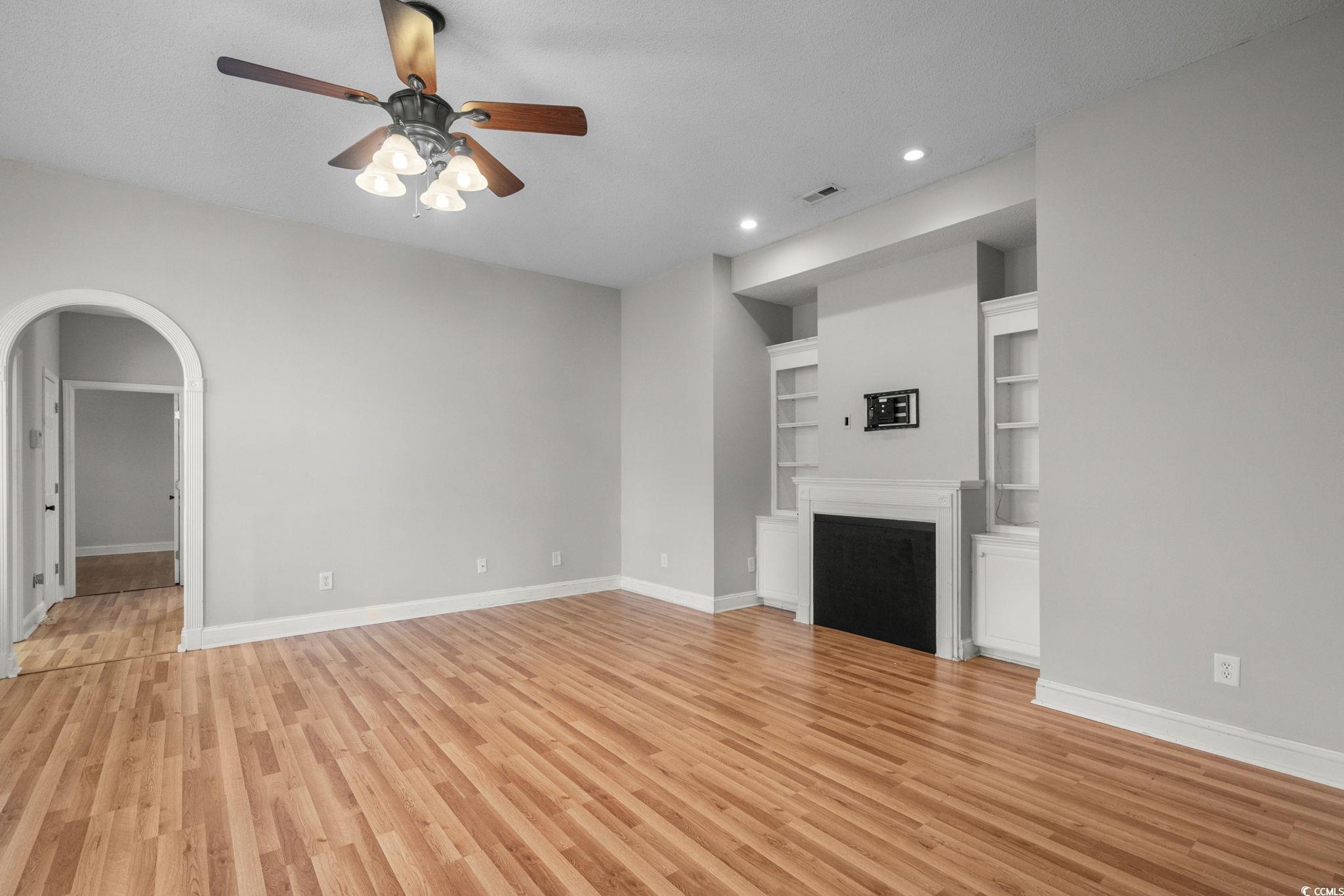 2723 Canvasback Trail Myrtle Beach, SC 29588 - Photo 9 of 40 Unfurnished living room featuring built in features, light wood-style flooring, arched walkways, a ceiling fan, and recessed lighting