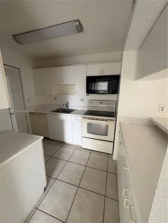 a kitchen with a sink a stove top oven and cabinets