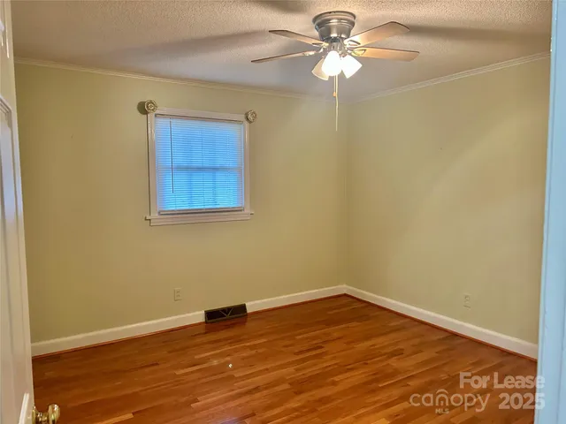 a view of a small space with wooden floor and a chandelier fan