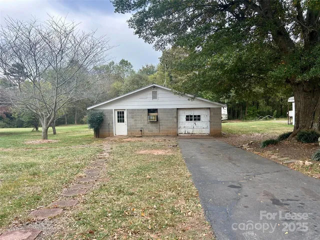a view of a house with a yard and large tree