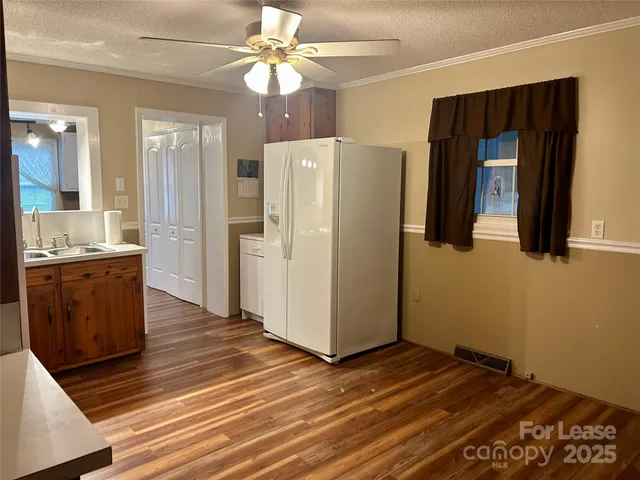 a view of a kitchen with wooden floor and a refrigerator