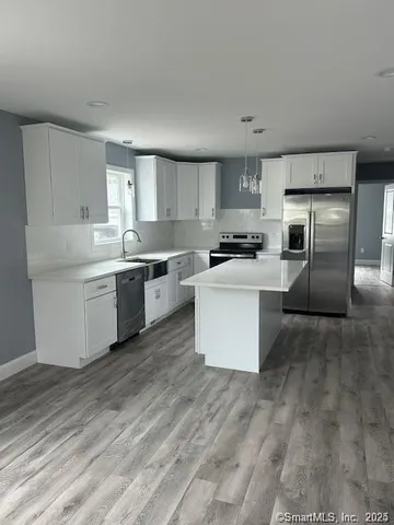 a kitchen with stainless steel appliances a sink a stove a refrigerator cabinets and a center island