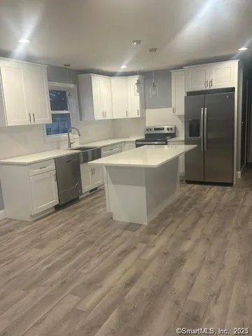 a large kitchen with kitchen island a sink a stove a refrigerator and white cabinets