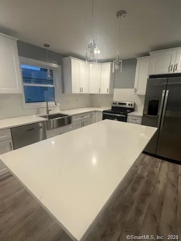 a kitchen with stainless steel appliances a sink a stove a microwave a sink a refrigerator and cabinets