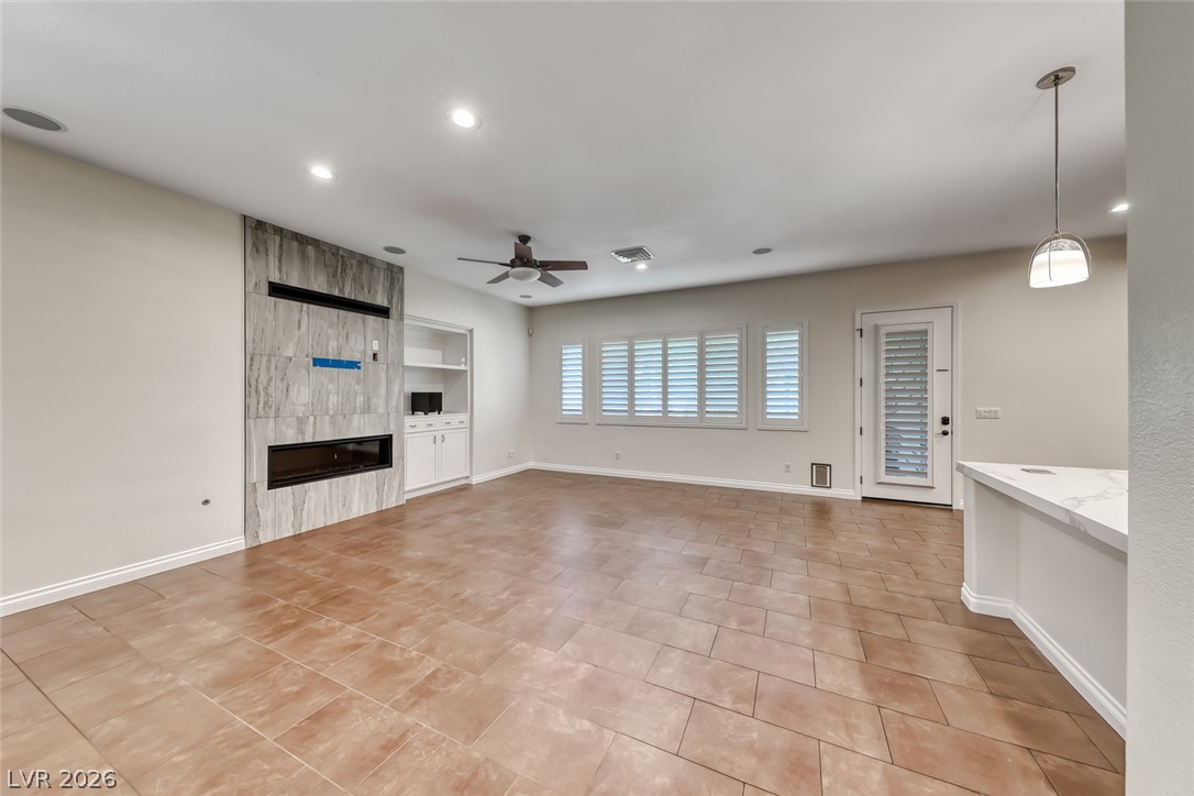 2122 Mooreview Street Henderson, NV 89012 - Photo 15 of 44 A well-lit living area features tiled flooring, a contemporary fireplace, and a built-in shelving unit, creating a functional and stylish space.