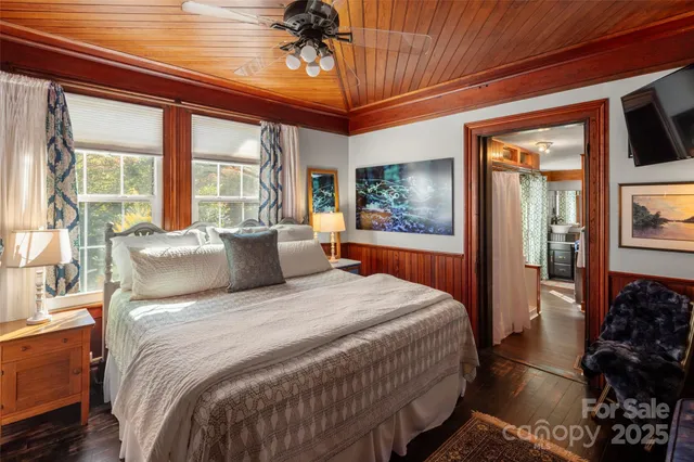 a bedroom with a large bed a flat screen tv and a large window with outer view