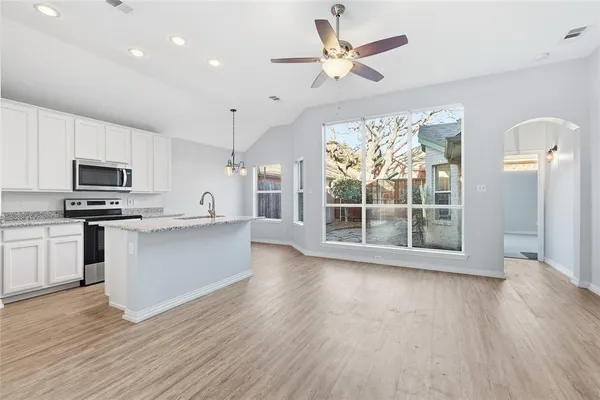 a large kitchen with hardwood floor a large window and stainless steel appliances