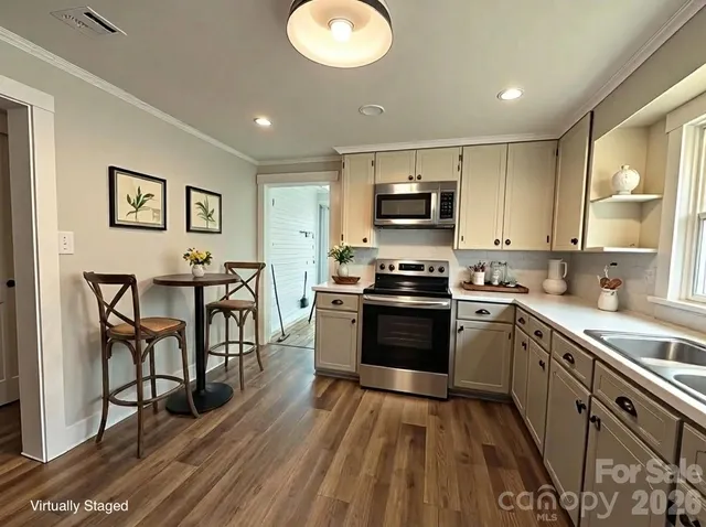 a kitchen with kitchen island granite countertop a stove top oven a sink dishwasher a dining table and chairs with wooden floor