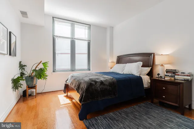 a bedroom with a bed and a potted plant on dresser