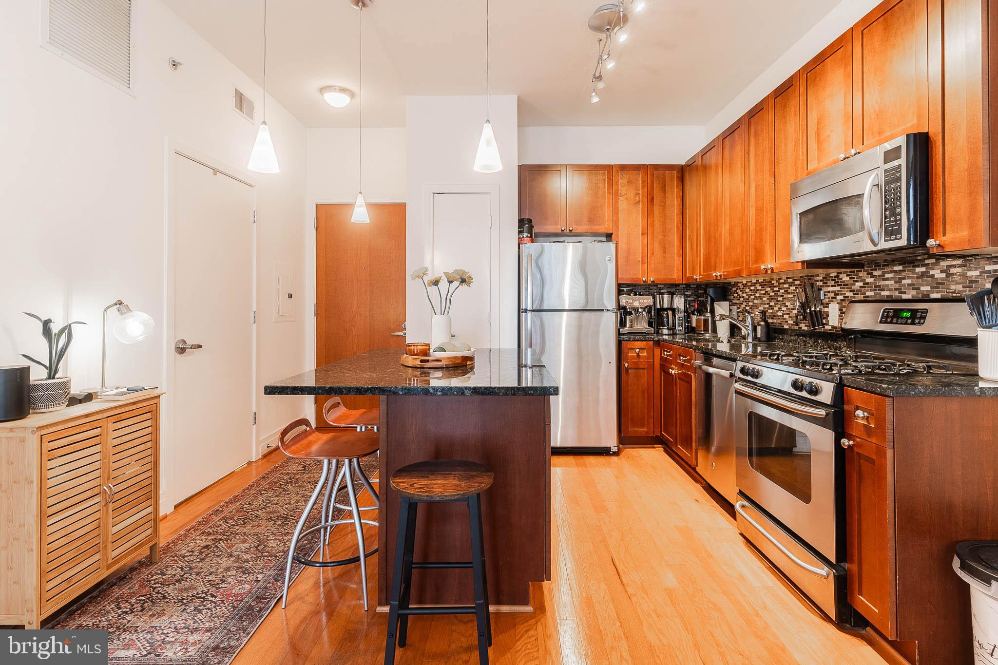 2120 Vermont Avenue Northwest, Unit 312 Washington, DC 20001 - Photo 2 of 16 a kitchen with stainless steel appliances granite countertop a refrigerator a stove top oven a sink and dishwasher
