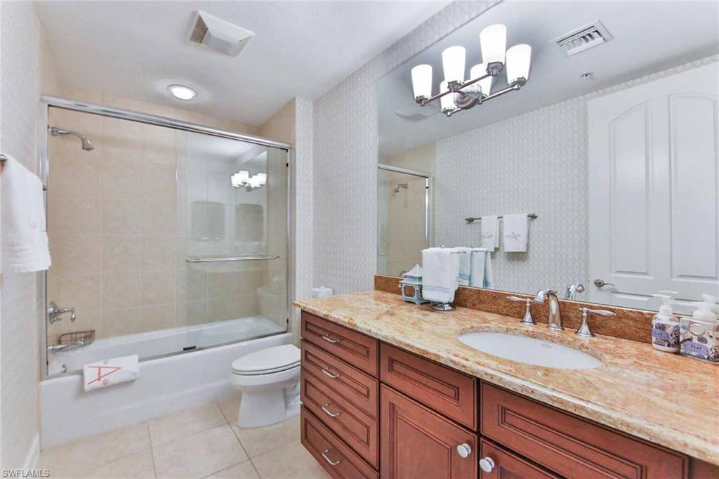 600 5th Avenue South, Unit A212 Naples, FL 34102 - Photo 19 of 21 a bathroom with a granite countertop sink a toilet and a large mirror