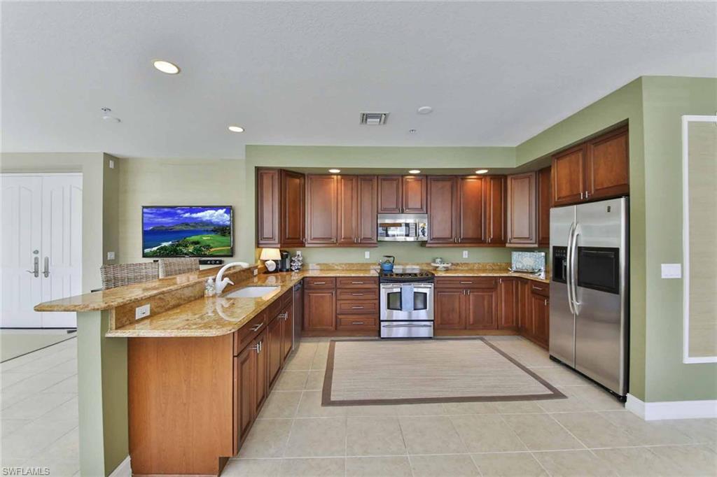 600 5th Avenue South, Unit A212 Naples, FL 34102 - Photo 5 of 21 a large kitchen with stainless steel appliances granite countertop a large counter top a stove a sink a refrigerator and a microwave