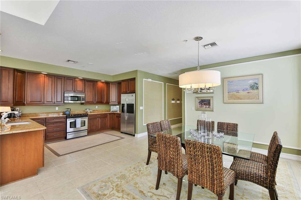 600 5th Avenue South, Unit A212 Naples, FL 34102 - Photo 6 of 21 a open kitchen with stainless steel appliances granite countertop a stove top oven a sink dishwasher a dining table and chairs with wooden floor