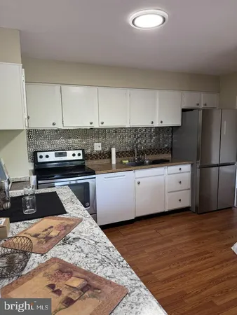 a kitchen with granite countertop a refrigerator and a stove top oven