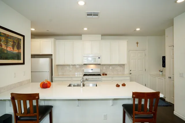 a kitchen with a refrigerator a stove a dining table and chairs