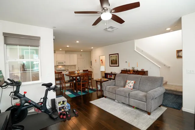 a living room with furniture kitchen view and a wooden floor