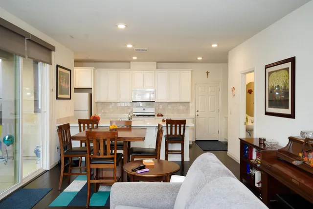 a living room with furniture and a dining table with kitchen appliances