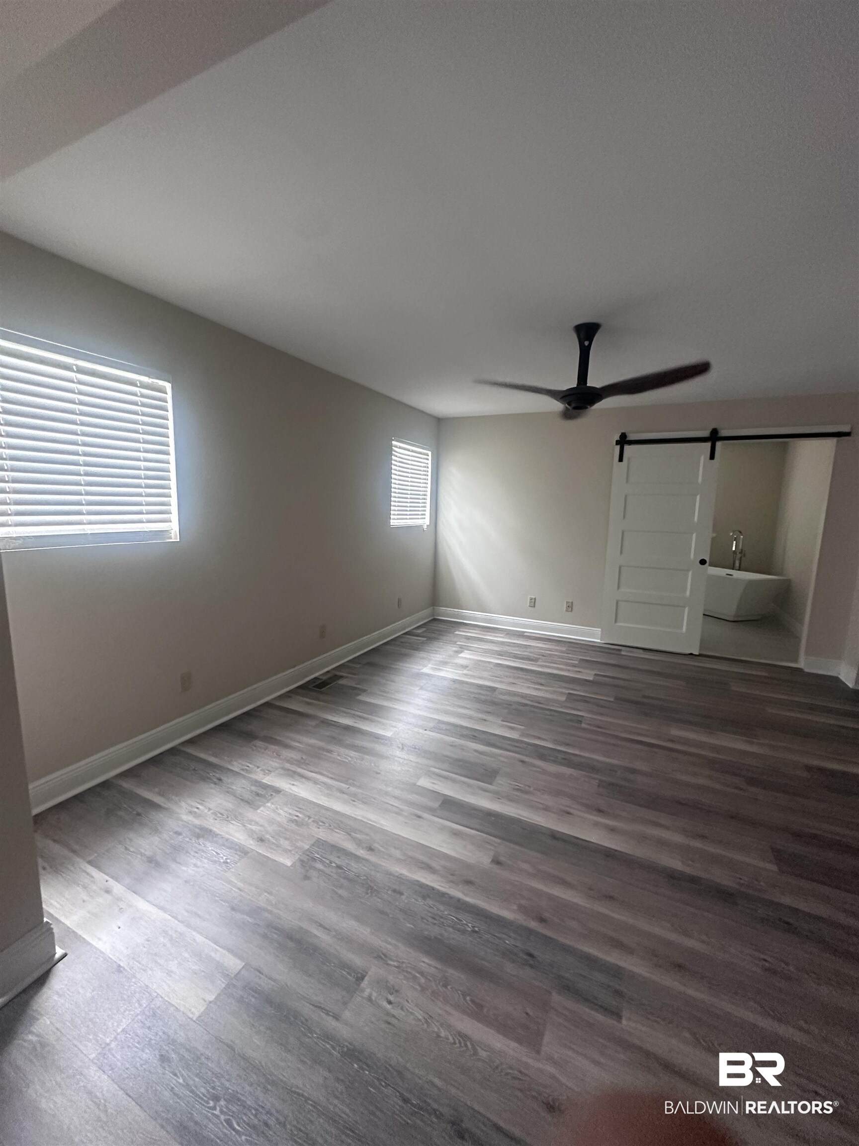 2785 Sowell Road Brewton, AL 36426 - Photo 9 of 24 Unfurnished bedroom featuring a barn door, dark wood-style flooring, and a ceiling fan