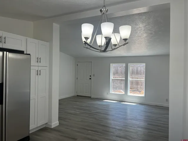 a view of a livingroom with a chandelier fan and windows
