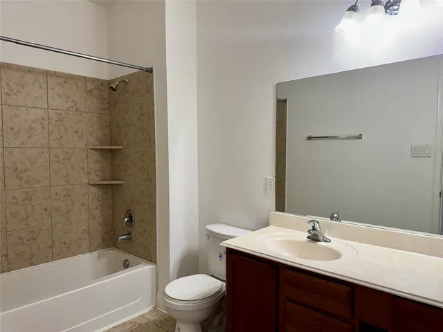 a bathroom with a bathtub shower sink vanity mirror and toilet
