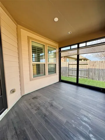 a view of an empty room with window and wooden floor