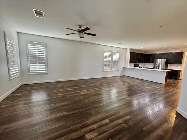 a view of an empty room with a window and wooden floor