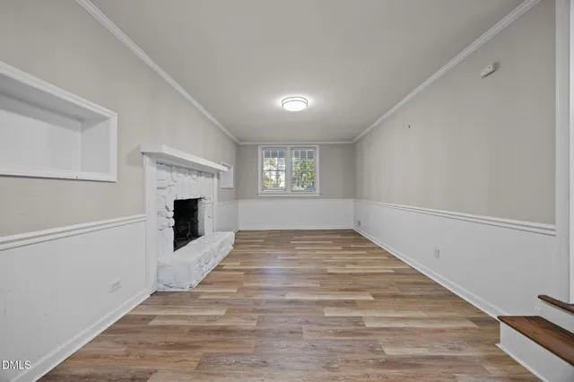 a view of empty room with wooden floor and fireplace