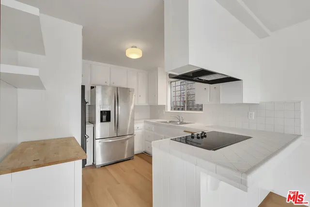 a kitchen with stainless steel appliances a refrigerator a sink a stove and white cabinets
