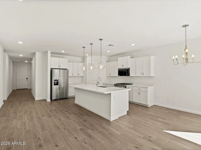 a view of kitchen with granite countertop a stove top oven a sink dishwasher and a refrigerator with wooden floor