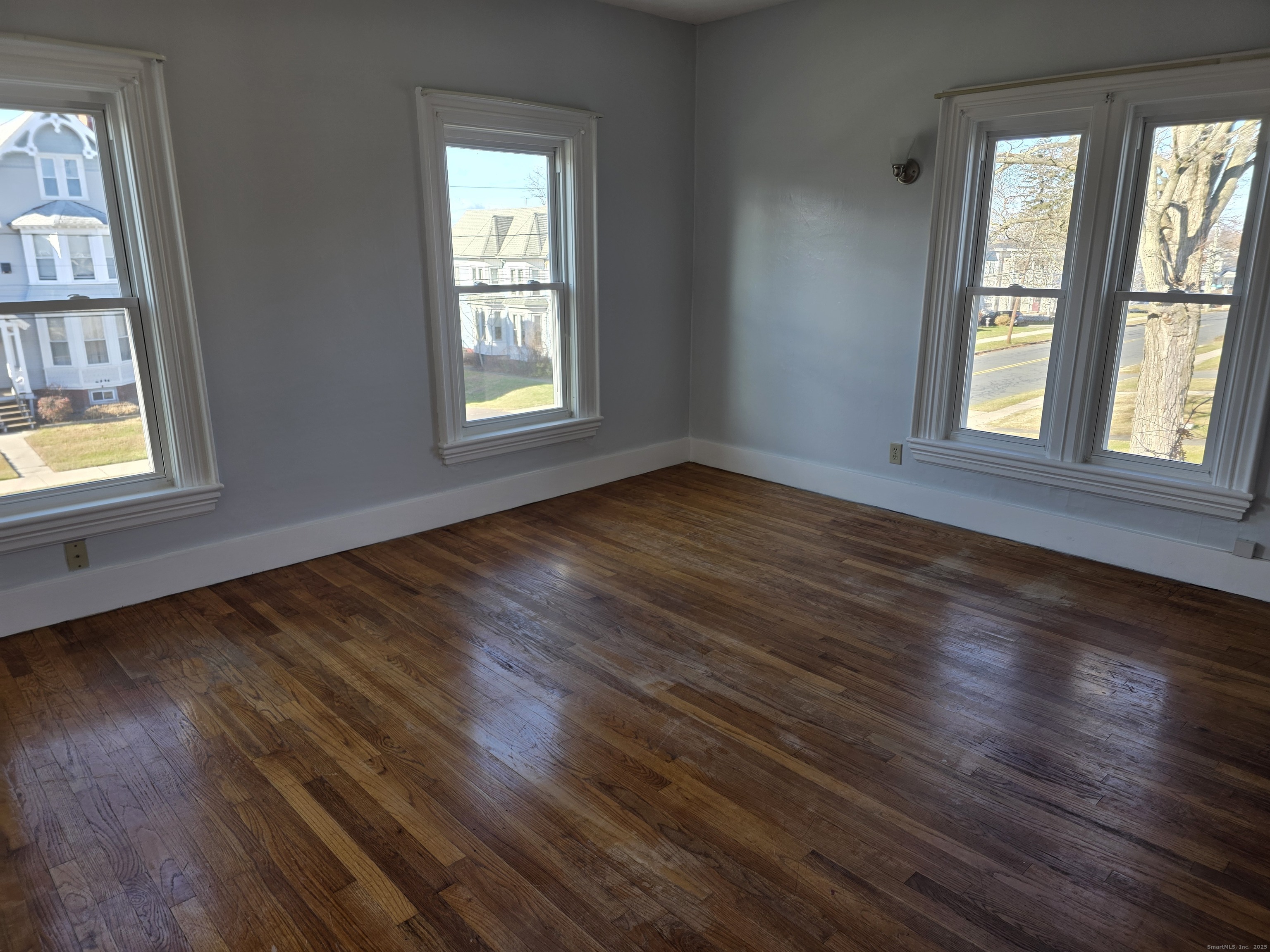 147 Pearl Street Enfield, CT 06082 - Photo 4 of 16 a view of an empty room with wooden floor and a window