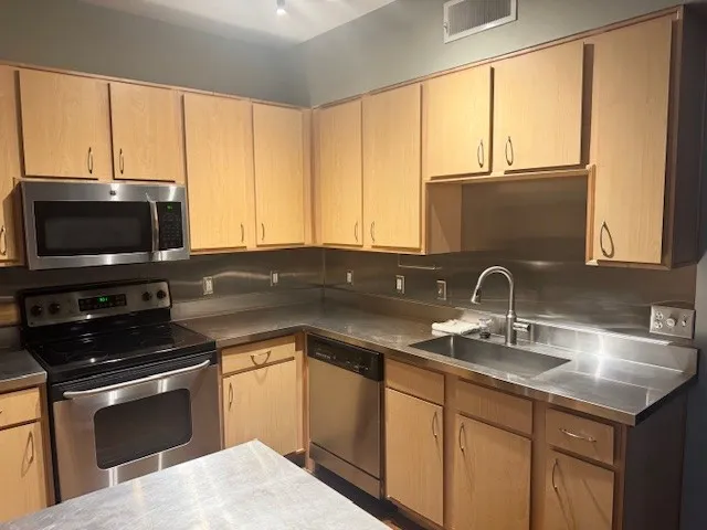 a kitchen with stainless steel appliances a sink stove and microwave
