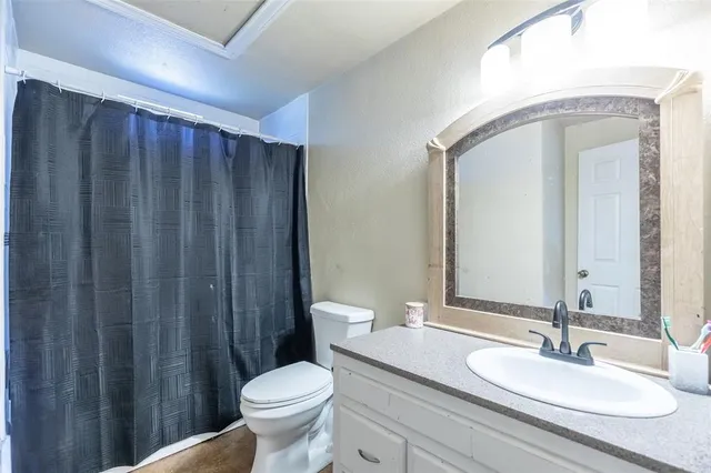a bathroom with a granite countertop toilet a sink and a mirror