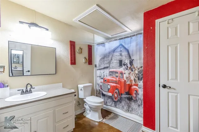 a bathroom with a granite countertop sink mirror vanity and toilet