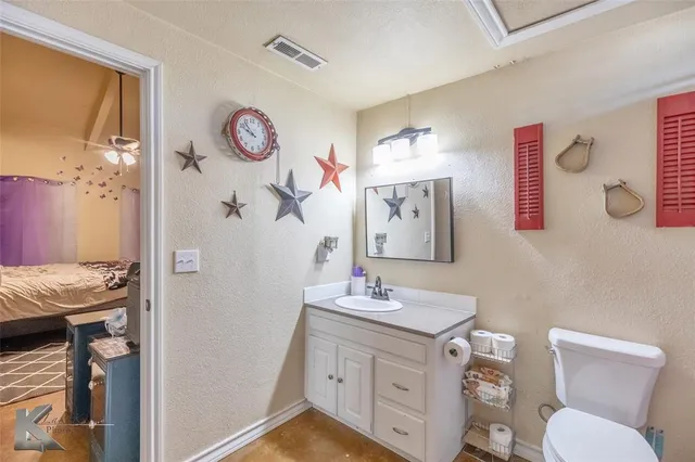 a bathroom with a granite countertop sink mirror vanity and toilet
