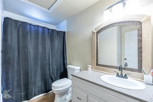 a bathroom with a granite countertop toilet a sink and a mirror