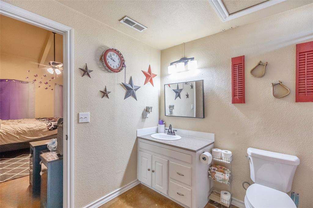 1502 Avenue North Anson, TX 79501 - Photo 17 of 20 a bathroom with a granite countertop sink mirror vanity and toilet