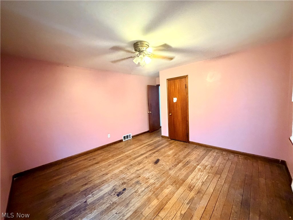 10506 Park Heights Road Cleveland, OH 44104 - Photo 11 of 22 Room featuring wood-finish flooring, a ceiling fan, baseboard trim, and two wood-paneled doors