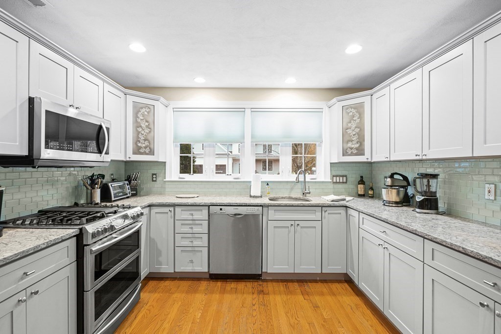 53 Elder Road Needham, MA 02494 - Photo 7 of 33 a kitchen with stainless steel appliances granite countertop a stove top oven a sink dishwasher and white cabinets with wooden floor