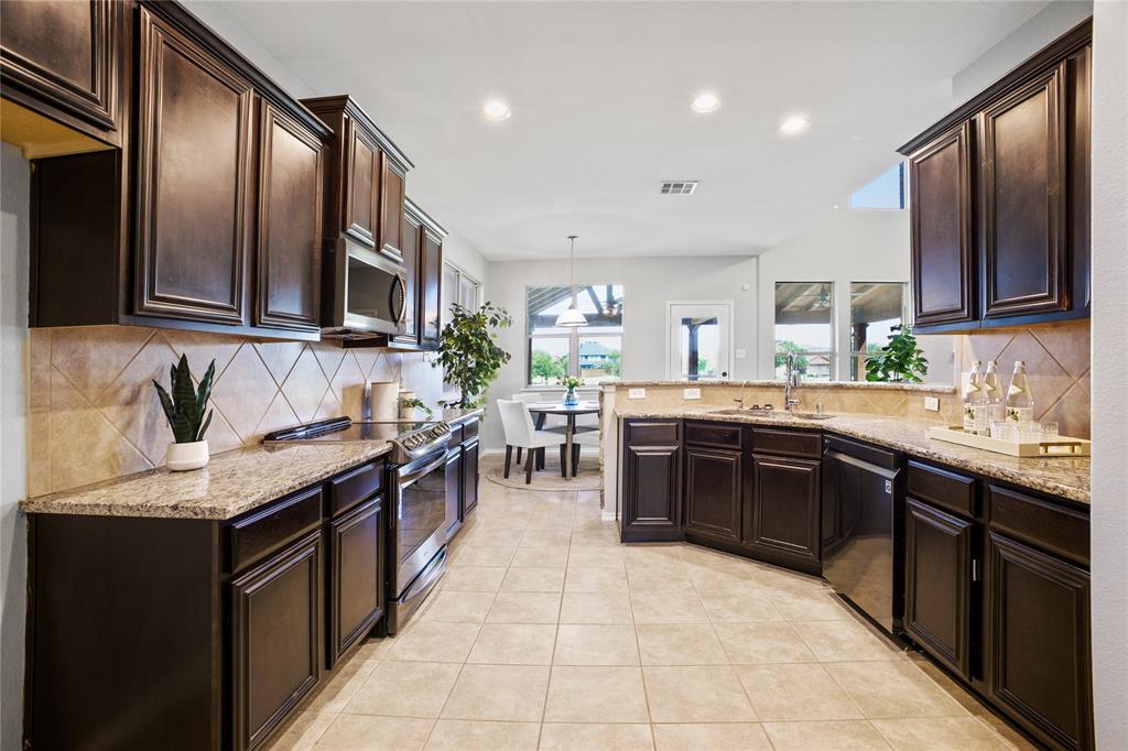 14904 Riverside Drive Little Elm, TX 75068 - Photo 7 of 28 a large kitchen with stainless steel appliances granite countertop a stove sink and cabinets