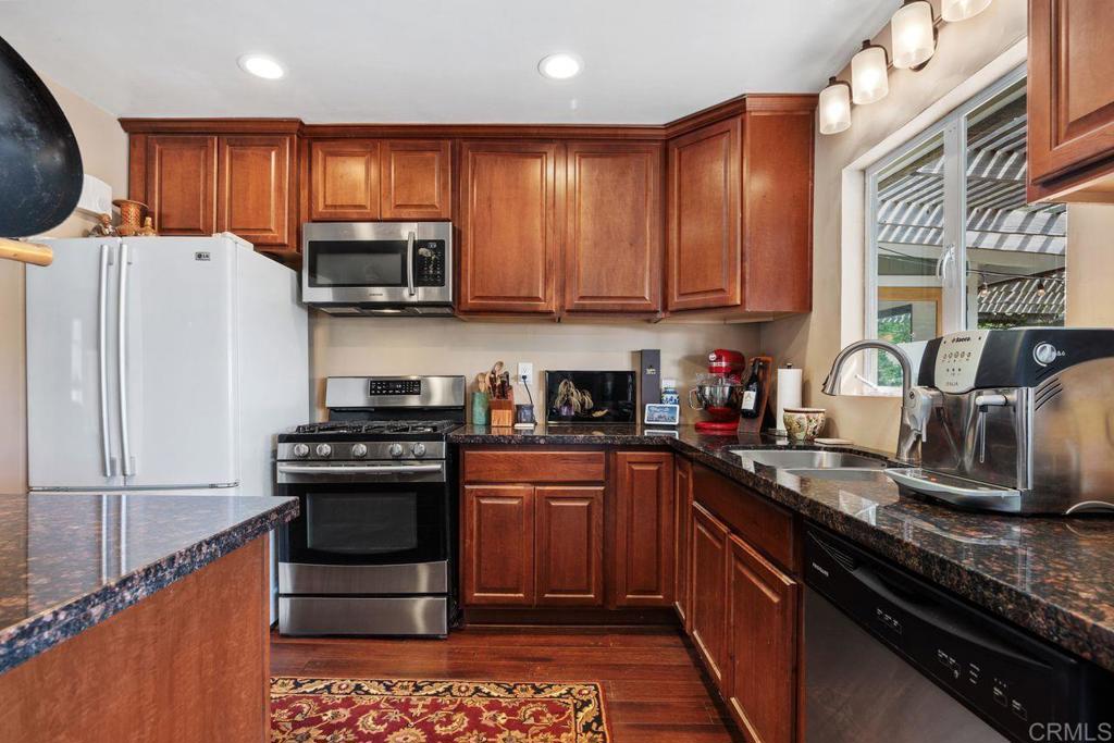 1107 Prospect Circle Vista, CA 92081 - Photo 17 of 52 a kitchen with stainless steel appliances granite countertop a stove a sink dishwasher a refrigerator and a microwave