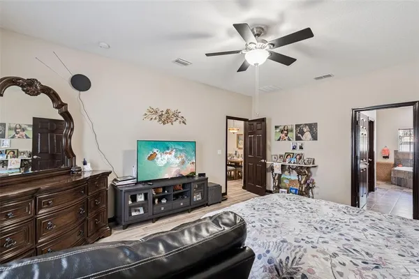 a bedroom with a bed and dresser with wooden floor