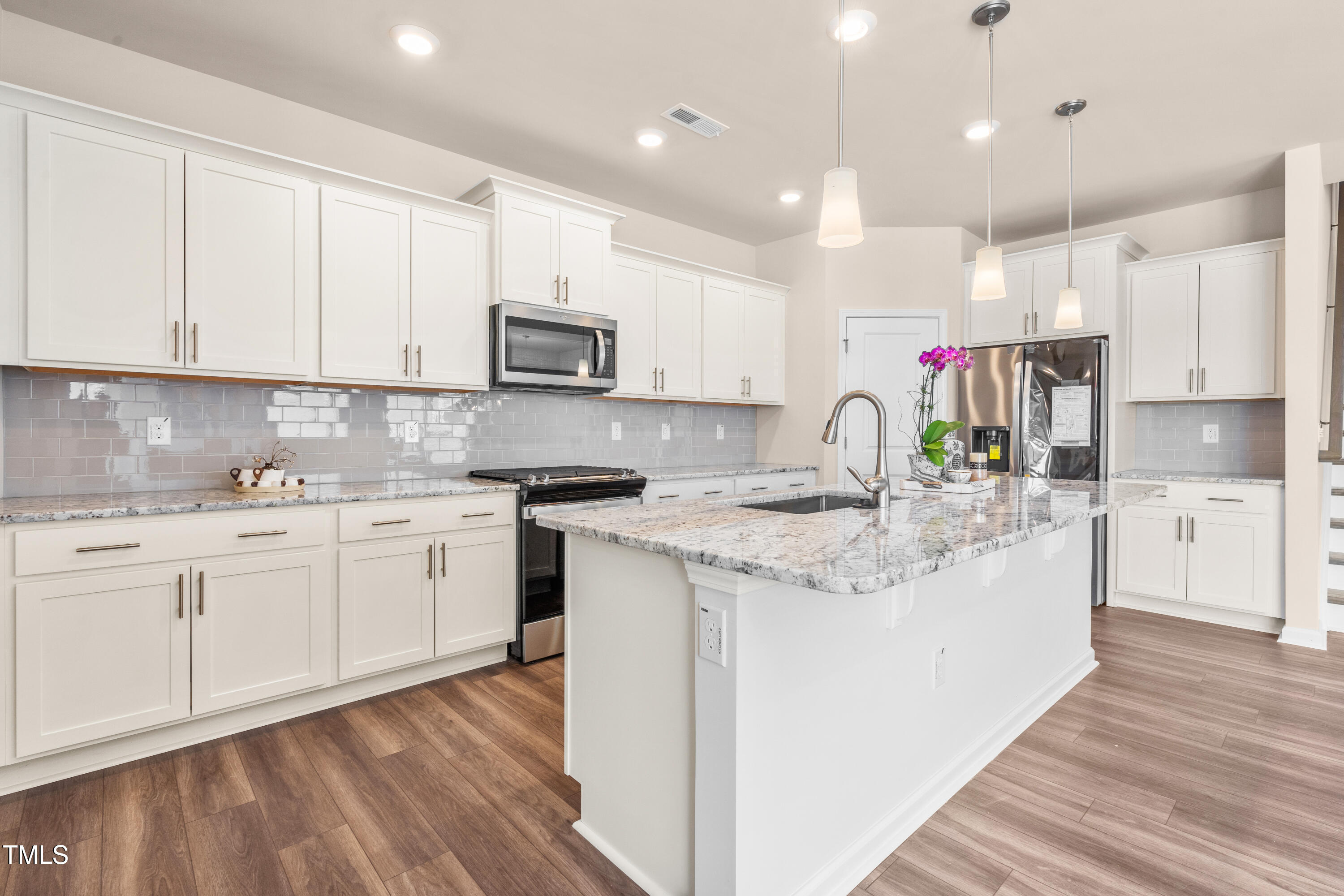 5800 Agrinio Way Raleigh, NC 27603 - Photo 6 of 38 a kitchen with kitchen island granite countertop a sink cabinets and wooden floor